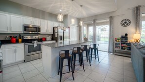 A modern kitchen with white cabinets, stainless steel appliances, and a central island with bar stools.
