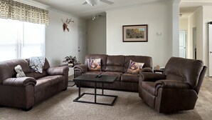 A living room with a brown leather sofa set, a coffee table, and a ceiling fan. - Lunker House By the Bay- Rural, Contemporary and Spacious-Moments from Downtown  (Sturgeon Bay)