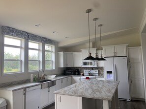 A modern kitchen with white cabinets, a marble countertop, and a built-in oven.