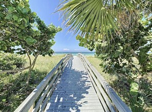 Une promenade en bois menant à une plage, avec un ciel dégagé.