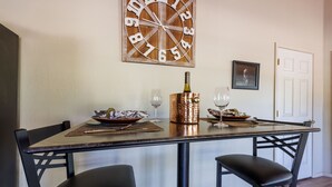 Une table à manger avec deux chaises, une bouteille de vin et deux verres à vin.
