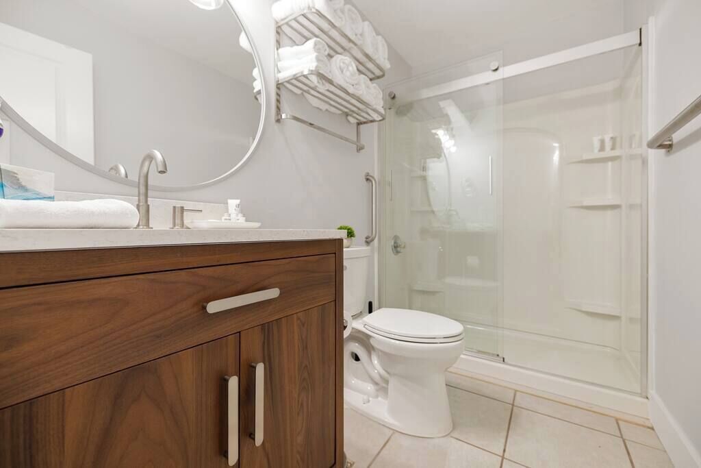 A modern bathroom with a wooden vanity, a glass shower enclosure, and a toilet.