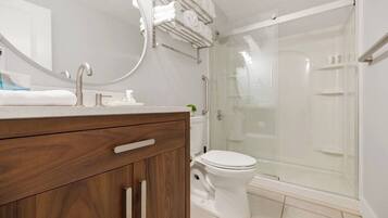 A modern bathroom with a wooden vanity, a glass shower enclosure, and a toilet.
