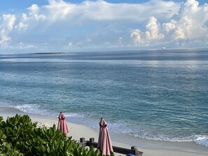 Una playa con una vista despejada del océano, una isla distante y un barco a lo lejos.