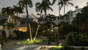 Patio de un resort con palmeras, piscina y un edificio de fachada azul y blanca.