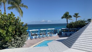 Zona de piscina con sillones de descanso, piscina y vista al océano.