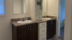 Une salle de bain avec deux lavabos, un grand miroir et un meuble avec des tiroirs.