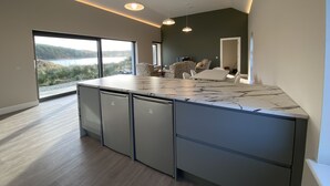 Una cucina moderna con un'isola grande, elettrodomestici integrati e vista su un lago.