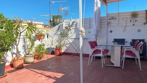 A rooftop patio with potted plants, a table with chairs, and a TV antenna. - Central Attic Apt Sleeps 4 with Patio (Almunecar)