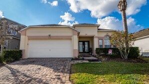A residential house with a garage, a well-maintained lawn, and a tall palm tree. - Pool Home In Gated Community Close to Disney (Davenport)