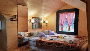 Ein gemütlicher Holzraum mit einem Bett, einem Fenster mit Karomustertvorhängen und Wandleuchten.