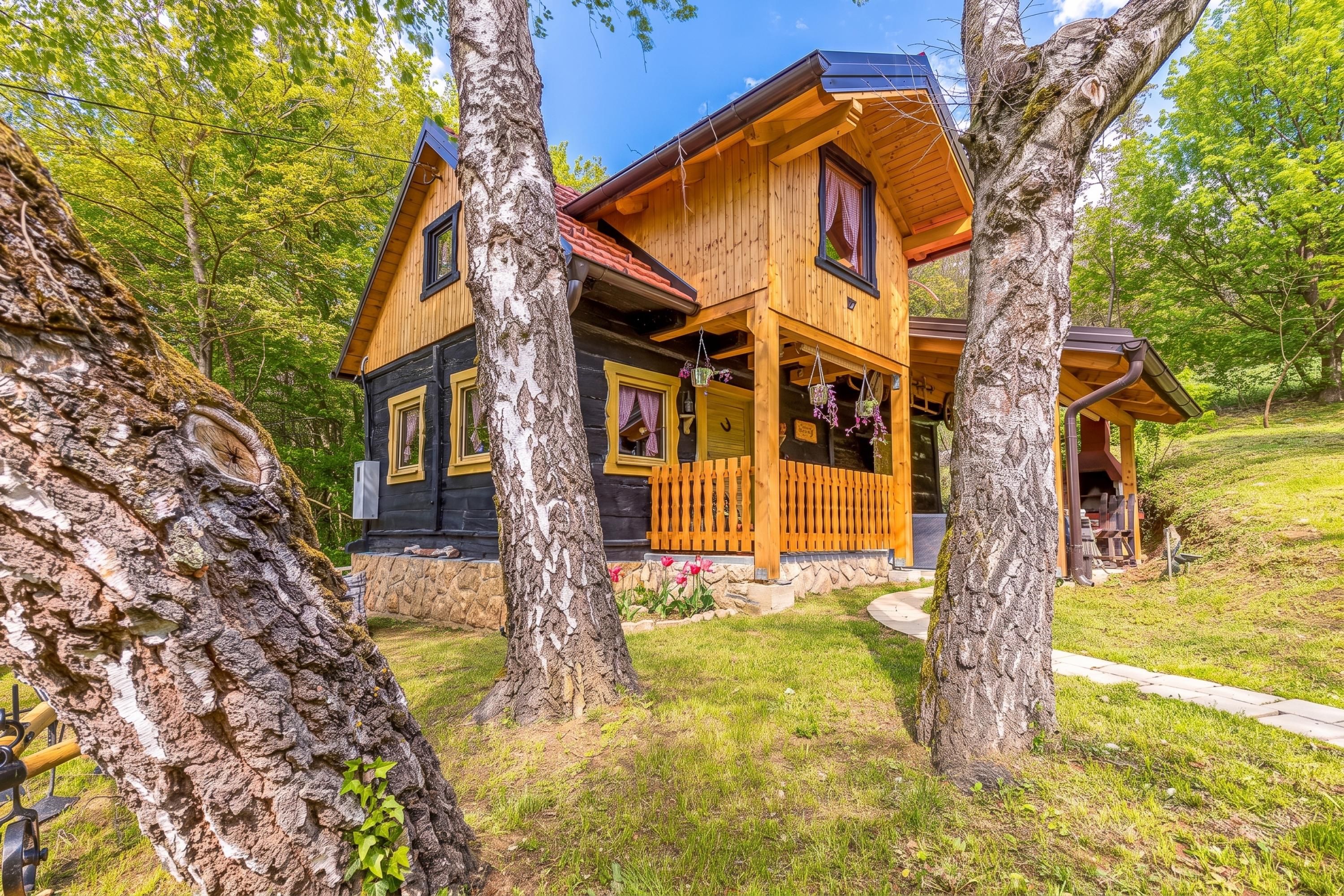 A wooden cabin with a porch, surrounded by trees.