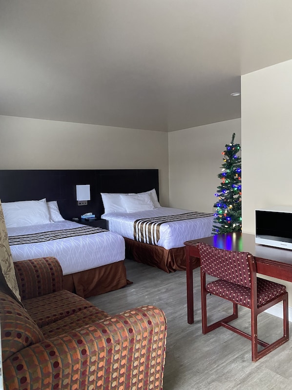 A hotel room with two beds, a desk, a chair, a Christmas tree, and a television. - Silver Maple Motel (Dysart et al)