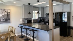 A modern kitchen with a central island, bar stools, and a refrigerator.