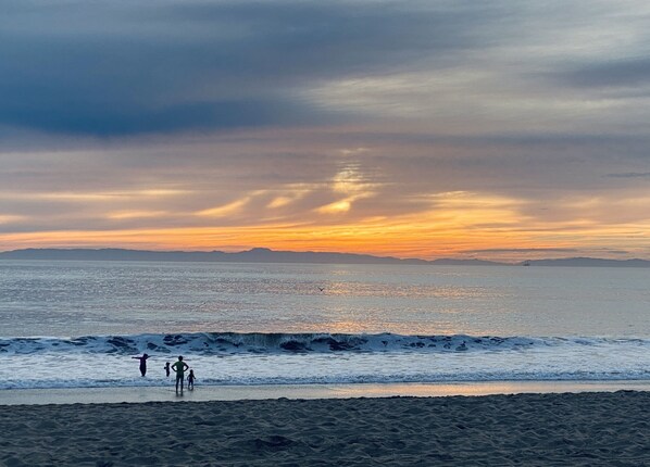 Une scène de plage avec des vagues et un coucher de soleil.