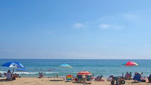 A beach with multiple umbrellas and beach chairs.