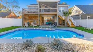 Ein zweistöckiges Haus mit Swimmingpool, überdachter Terrasse und einem umzäunten Garten.