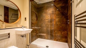 Un bagno moderno con doccia vetrata, lavandino bianco e un grande specchio.