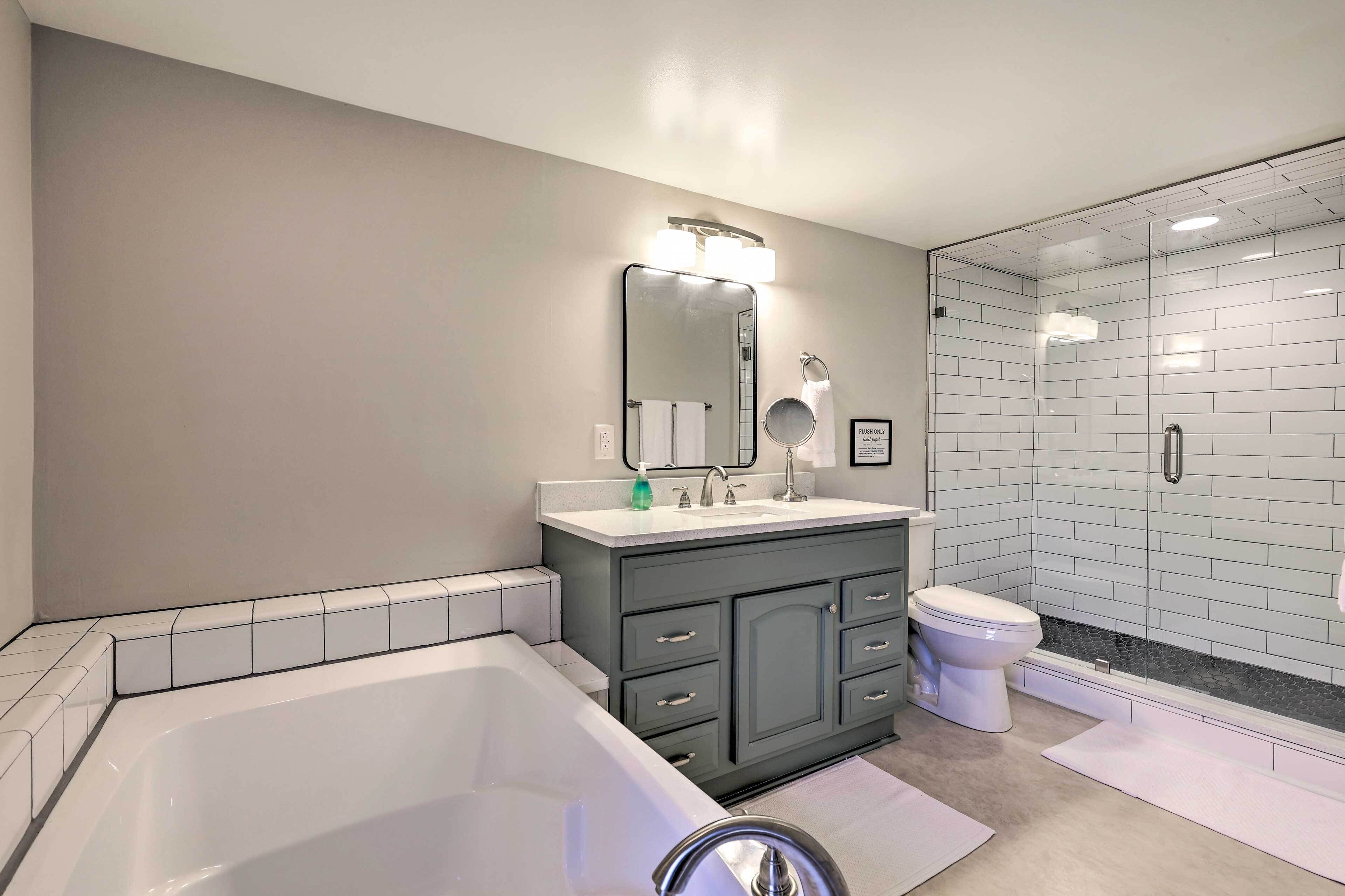 A modern bathroom with a bathtub, vanity, toilet, and a glass shower enclosure.