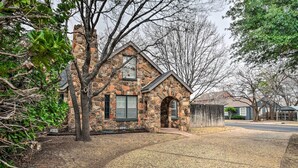 A stone house with a chimney, a porch, and a gravel driveway.