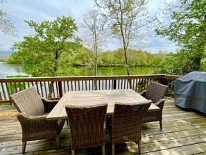 A wooden deck with a table and wicker chairs overlooking a body of water with trees. - Waterfront, Luxury Panoramic View, Fast Wi-Fi, Private River Access Steps Away! (Luray)