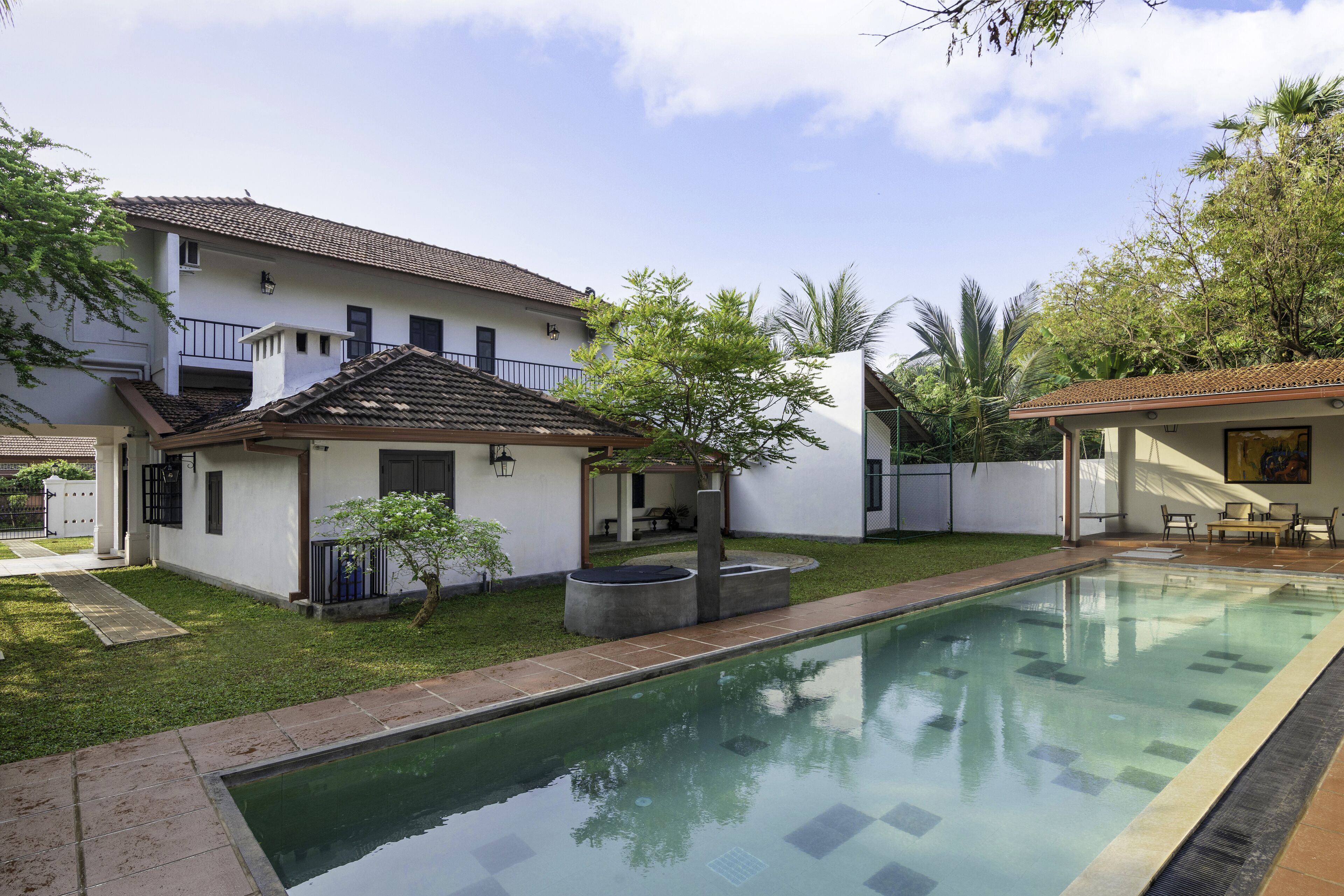 A residential property with a swimming pool, a covered patio, and a well-maintained lawn.