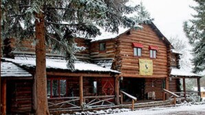 A log cabin with a porch and a snow-covered roof. - Lumbermens Village (Lakeside)