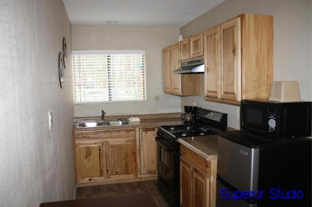 A kitchen with wooden cabinets, a stove, a microwave, and a sink.