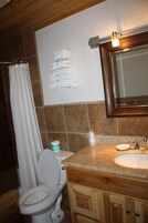Un baño con inodoro, lavamanos y armarios de madera.