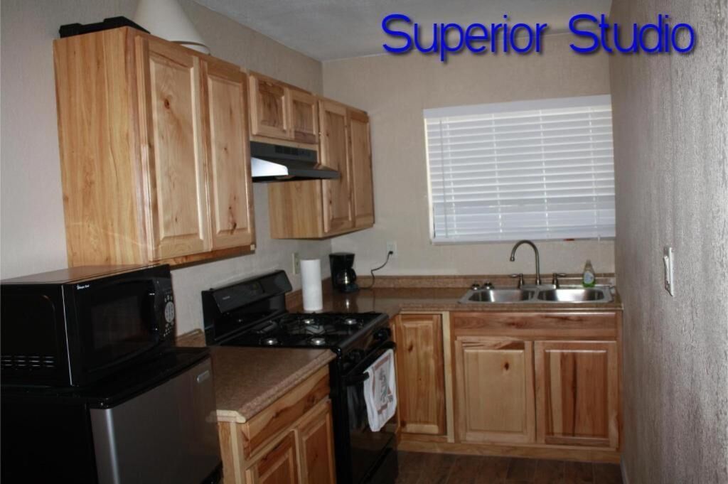 A compact kitchen with wooden cabinets, a stove, a microwave, and a sink.