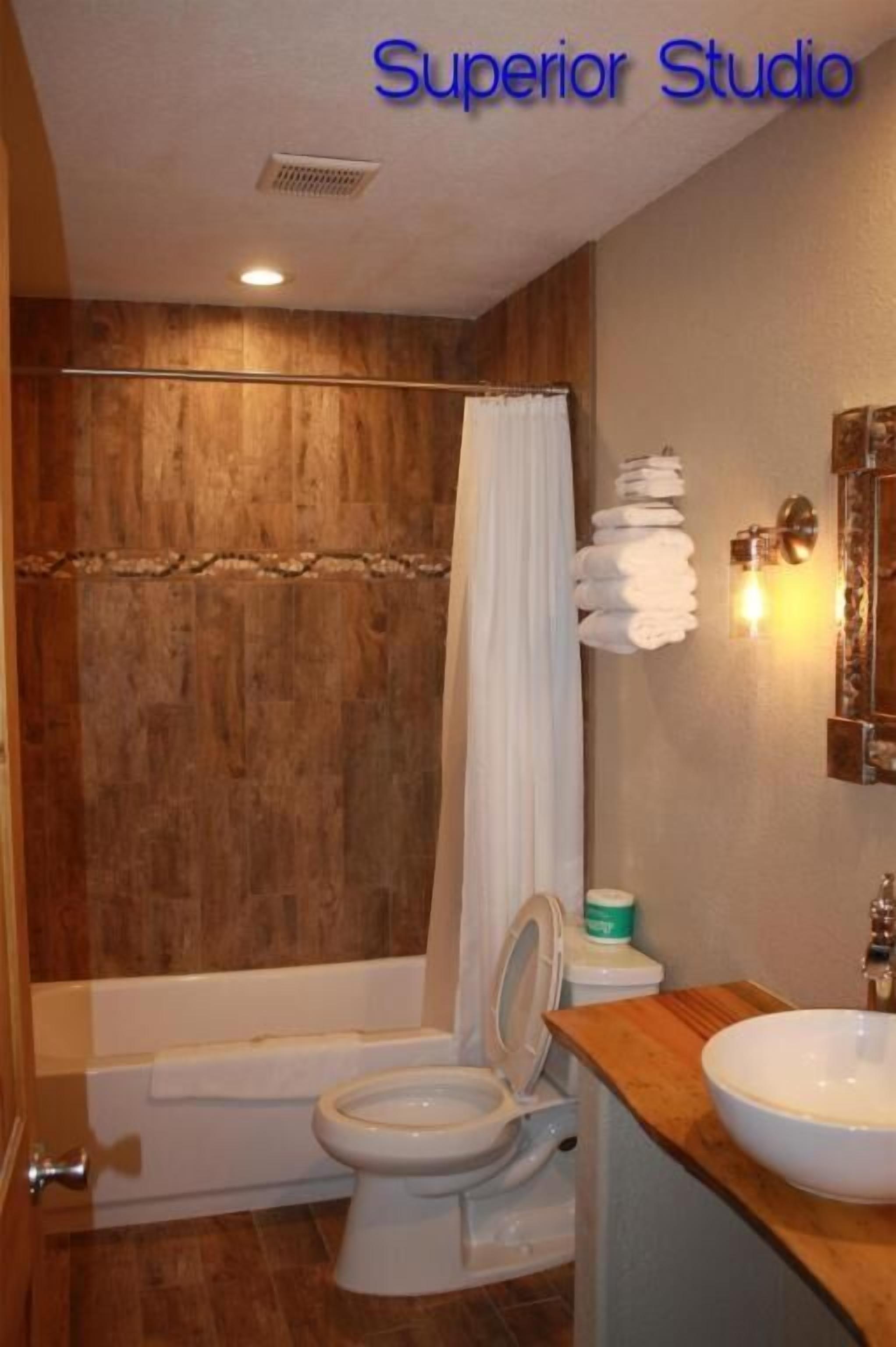 A bathroom with a wooden wall, a bathtub, a toilet, and a sink.