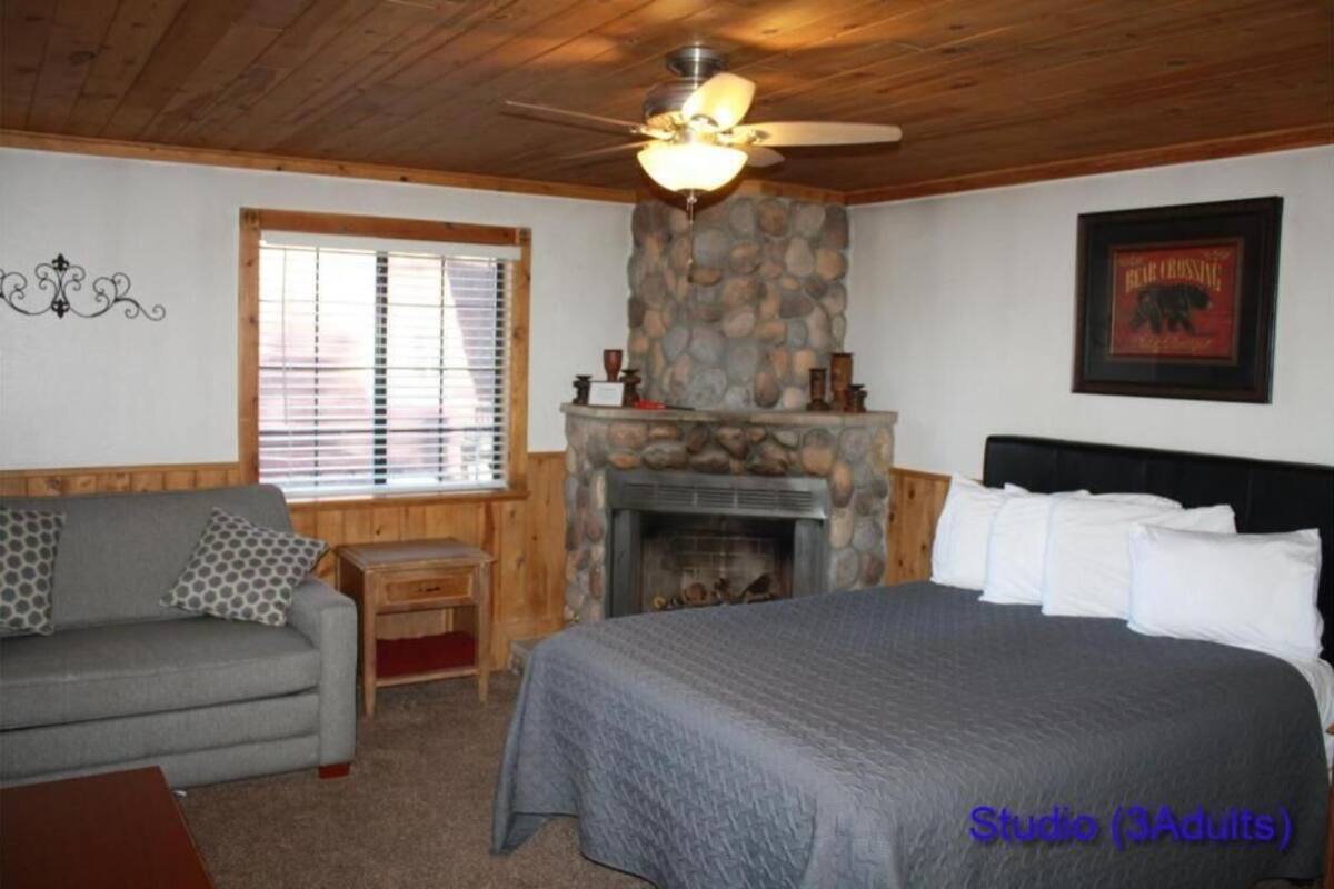 A cozy room with a bed, a fireplace, a sofa, and a ceiling fan.