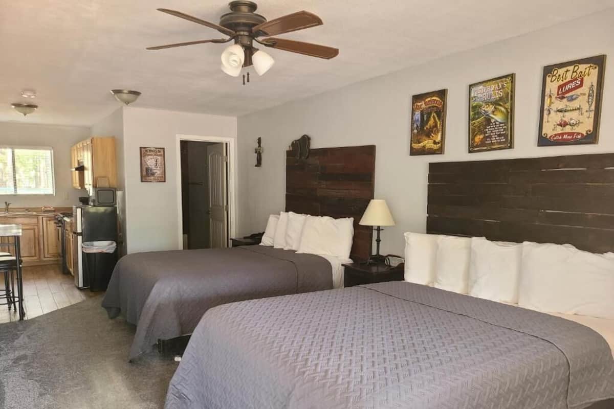 A bedroom with two beds, a ceiling fan, and wall-mounted artwork.