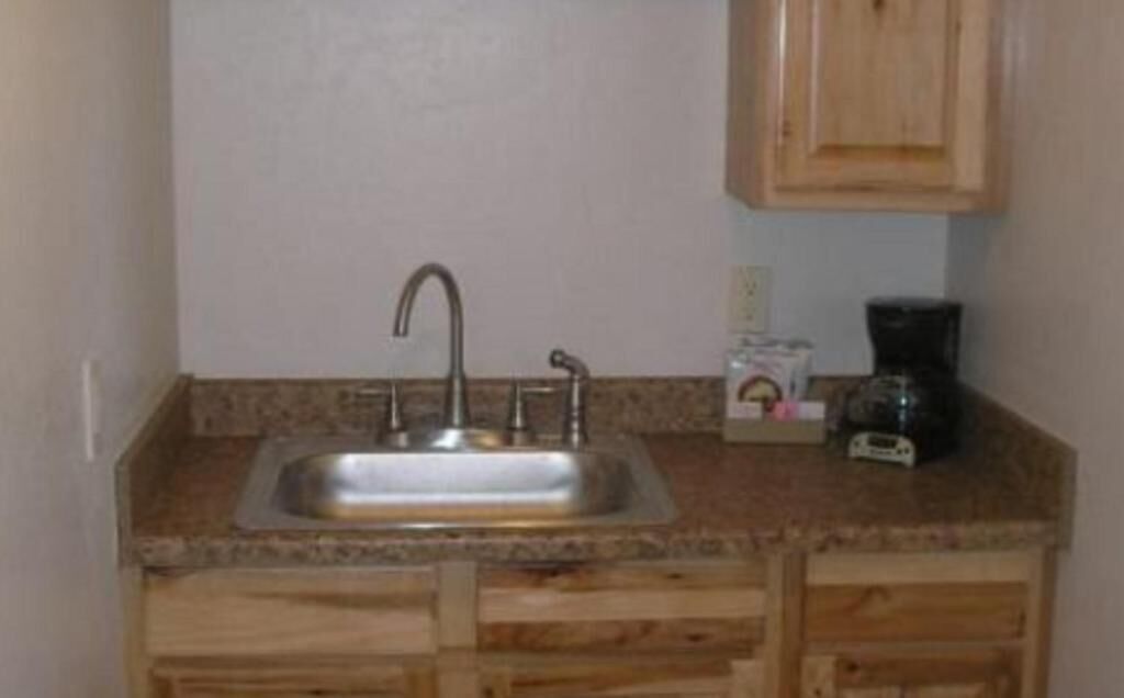 A small kitchen with a sink, wooden cabinets, and a coffee maker.