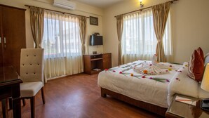 Ein Hotelzimmer mit Bett, Schreibtisch, Stuhl und Fernseher.