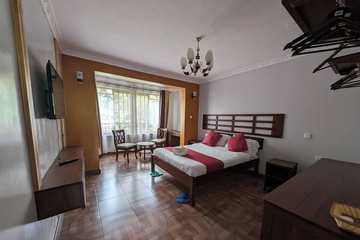 A hotel room with a bed, a desk, a chair, and a television.
