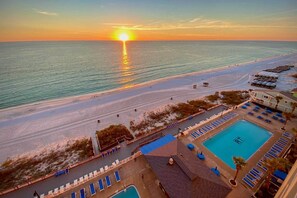 Een resort met een zwembad, toegang tot het strand en uitzicht op de zonsondergang.