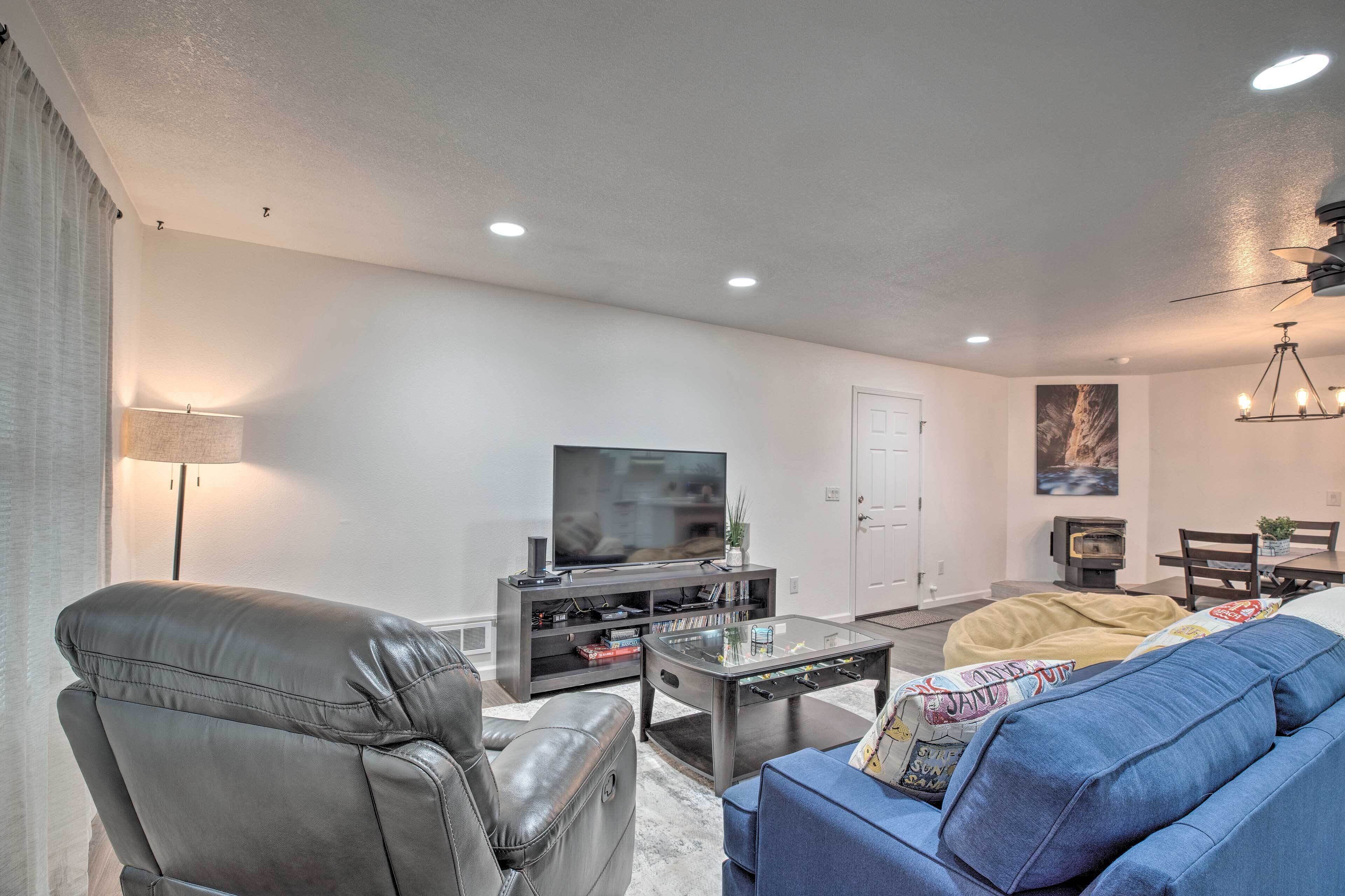 A modern living room with a leather sofa, a blue couch, a coffee table, a TV on a stand, and a dining area with a table and chairs.