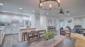 A modern kitchen with white cabinets, a central island, and a dining area with a table and chairs.