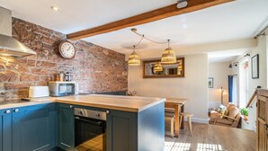 A kitchen with a stone wall, wooden beams, and pendant lighting.