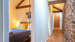 A bedroom with a wooden bed, a nightstand, a lamp, and a painting on the wall.