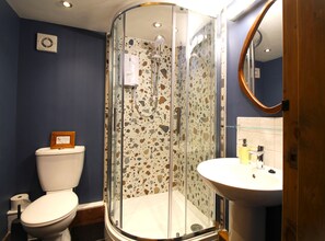 Een badkamer met een douchecabine van glas, een toilet en een wastafel.