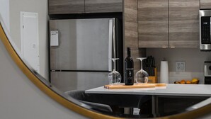 A modern kitchen with a stainless steel refrigerator, wooden cabinets, and a white countertop. - Lake Okanagan beach condo w/ private buoy, AC, heated outdoor pool, patio, SUPs (Vernon)