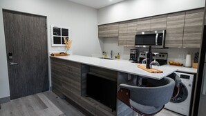 A modern kitchen with a built-in microwave, oven, and washing machine. - Lake Okanagan beach condo w/ private buoy, AC, heated outdoor pool, patio, SUPs (Vernon)