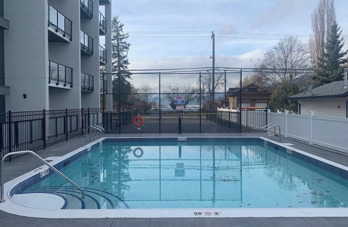 Una piscina con un área cercada, un flotador salvavidas y un cartel al fondo.