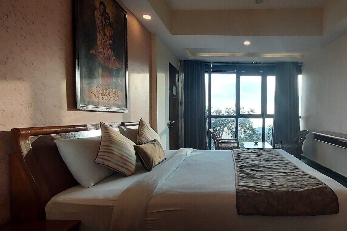 Ein Hotelzimmer mit Bett, Fernseher, Schreibtisch und Fenster mit Blick.