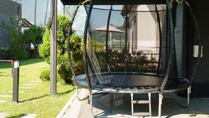 Un trampolín con red de seguridad en un patio trasero.