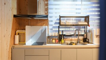 Una cocina con horno empotrado, lavamanos y ventana con persianas.