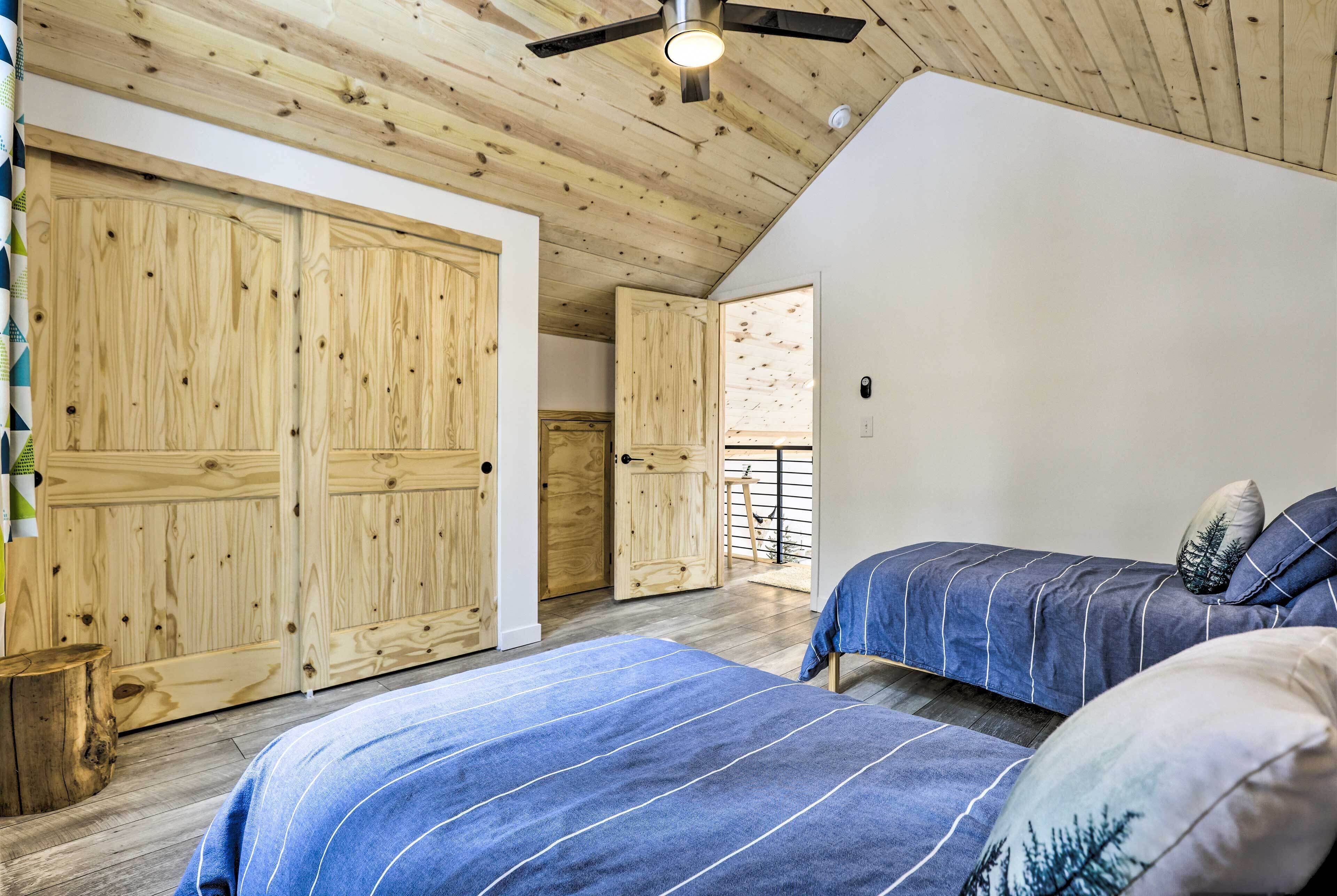 A bedroom with wooden ceiling beams, a sloped ceiling fan, and a large wardrobe.