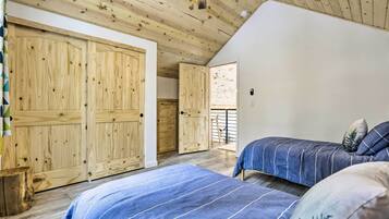 A bedroom with wooden ceiling beams, a sloped ceiling fan, and a large wardrobe.